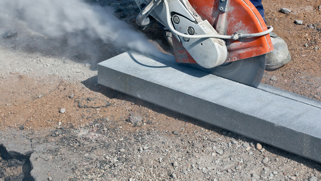 Opérateur réalisant sciage béton armé avec disque diamant