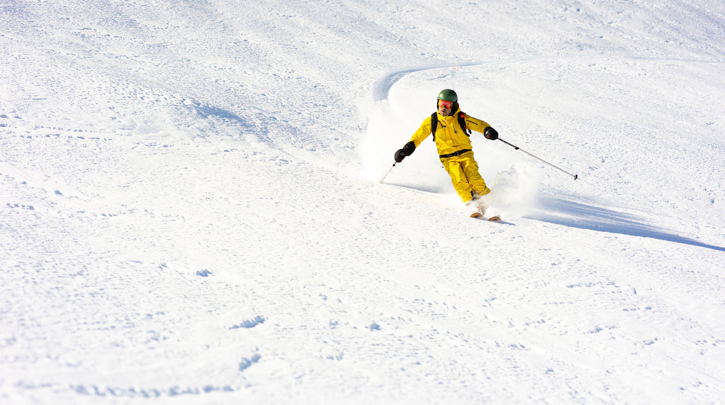 Personne consultant des offres de location de ski sur tablette avec carnet de notes et café, dans une ambiance décontractée de planification de séjour à la montagne