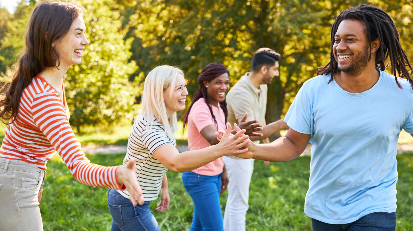 Équipe de cinq professionnels en session de travail collaboratif autour d'une table dans le parc verdoyant d'un domaine privatisé, environnement extérieur calme et naturel, discussion active en séminaire d'entreprise