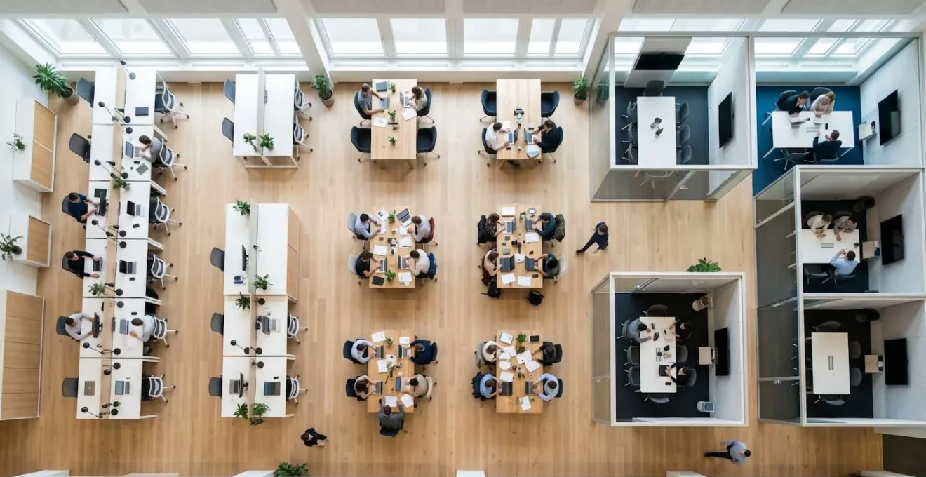 Vue aérienne d'un espace de coworking moderne avec différents postes de travail illustrant les phases de croissance d'entreprise