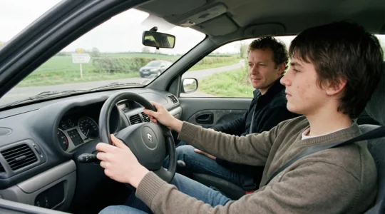 Jeune conducteur au volant accompagné d'un superviseur adulte lors d'une séance de conduite supervisée sur une route française